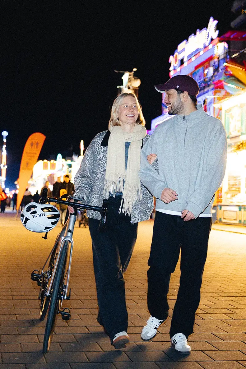 Ein Junges Paar im Stadtleben in der Nacht. Die Frau schiebt ihr Dienstrad