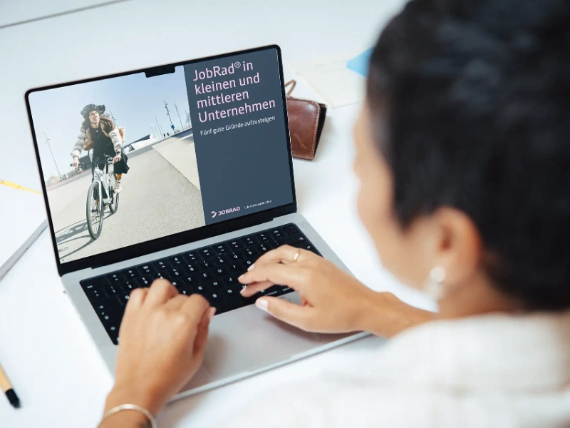 Frau sitzt im Büro vor Laptop und liest JobRad Whitepaper