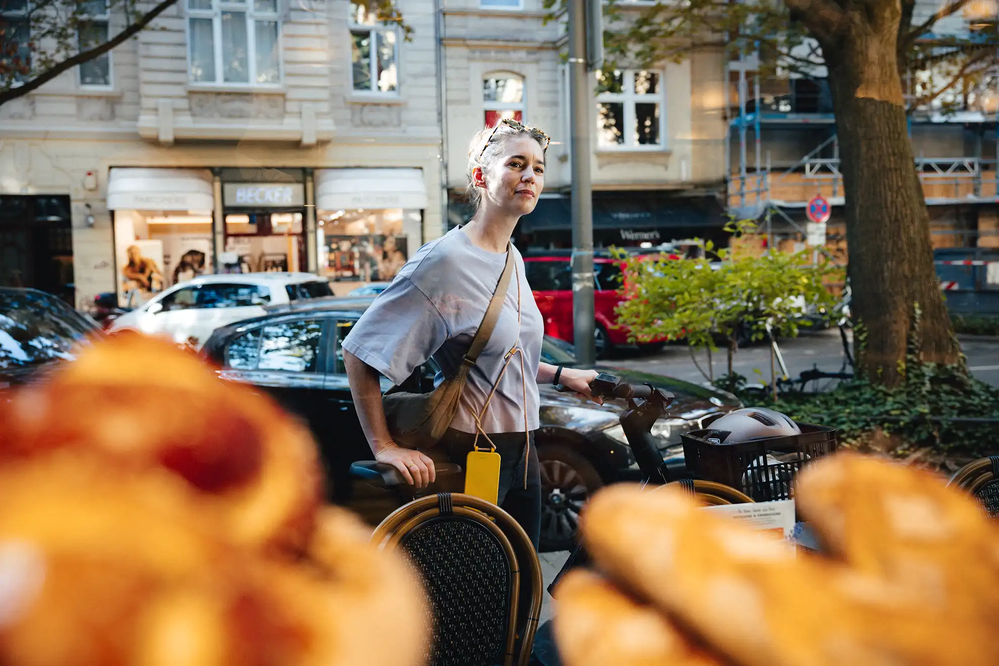 Eine Frau schiebt ihr Dienstrad an einer Bäckerei vorbei