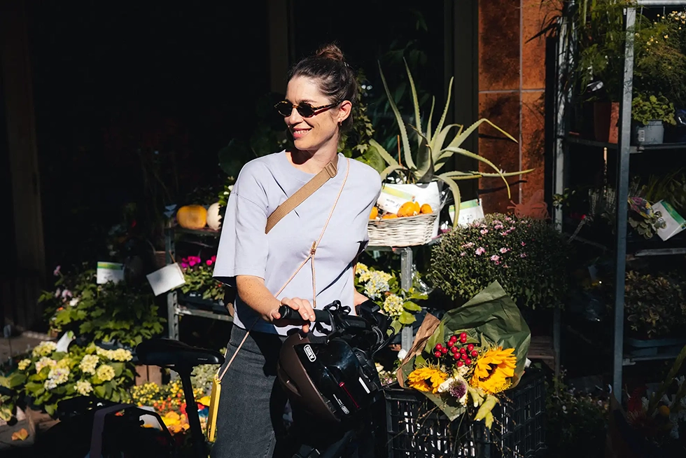 Frau steht mit ihrem Dienstrad vorm Blumenladen.
